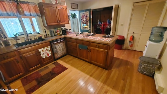 kitchen featuring sink, tile countertops, stainless steel dishwasher, kitchen peninsula, and light hardwood / wood-style floors