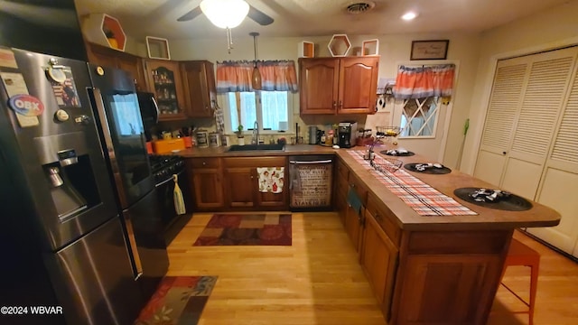 kitchen with dishwashing machine, sink, light hardwood / wood-style flooring, ceiling fan, and stainless steel fridge with ice dispenser