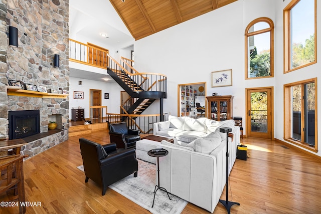 living room featuring a stone fireplace, plenty of natural light, high vaulted ceiling, and wooden ceiling