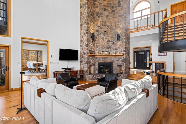 living room featuring a fireplace, a towering ceiling, and light hardwood / wood-style floors