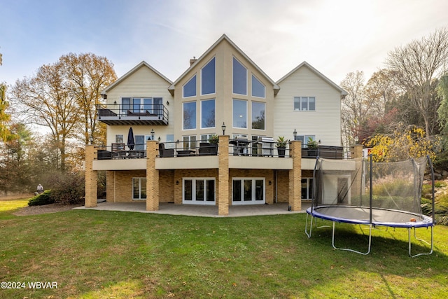 back of house featuring a patio area, a yard, french doors, and a trampoline