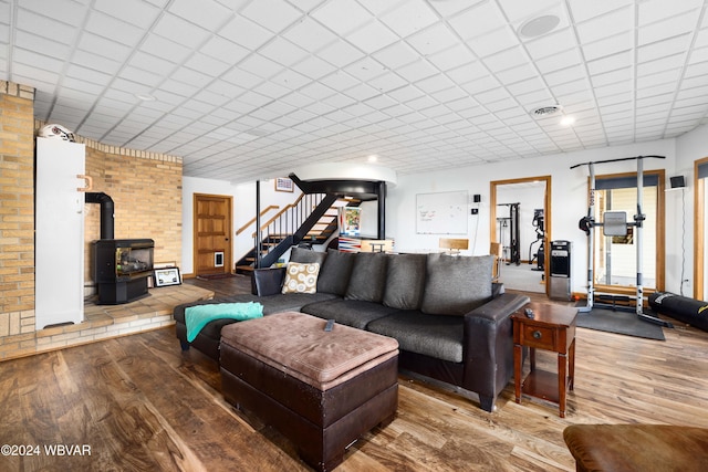 living room featuring hardwood / wood-style flooring, a wood stove, and a drop ceiling