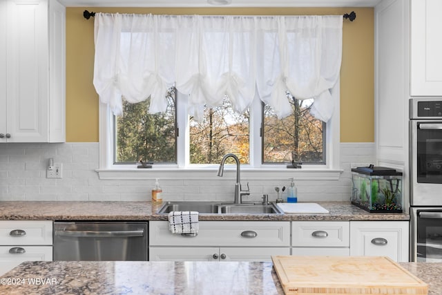 kitchen featuring dishwasher, white cabinets, tasteful backsplash, and sink