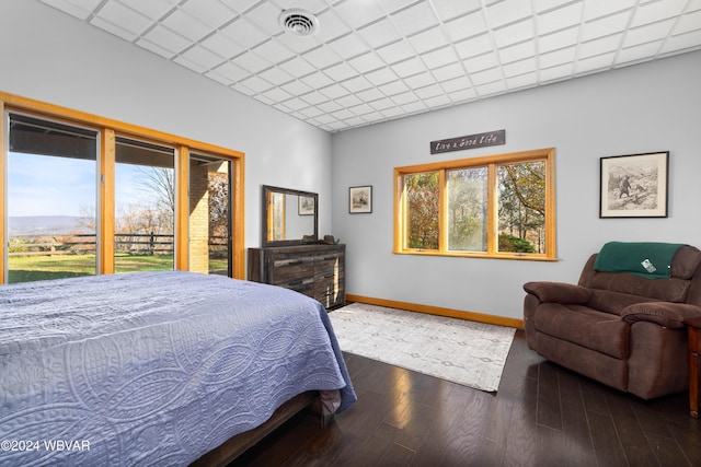 bedroom with a paneled ceiling, dark hardwood / wood-style flooring, and access to outside