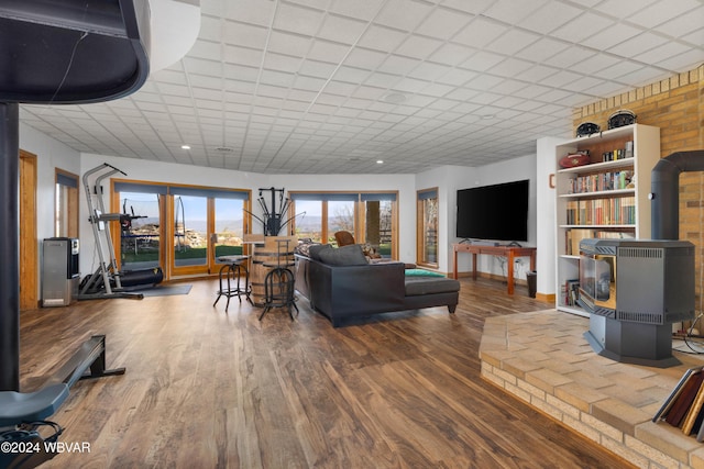 living room with a wood stove, a paneled ceiling, and hardwood / wood-style floors