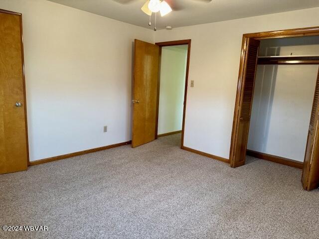 unfurnished bedroom with light carpet, a closet, and ceiling fan