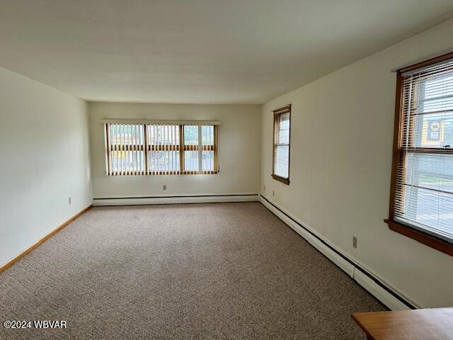 spare room with baseboard heating and carpet