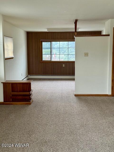 carpeted empty room featuring baseboard heating