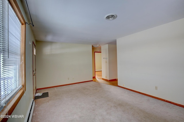 empty room with carpet, visible vents, baseboard heating, and baseboards