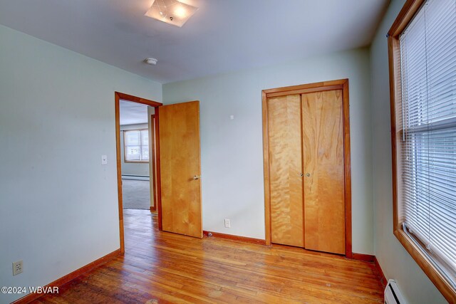 65 Spring St, Lock Haven, PA 17745 - unfurnished bedroom featuring a baseboard heating unit, light wood-style floors, and a closet