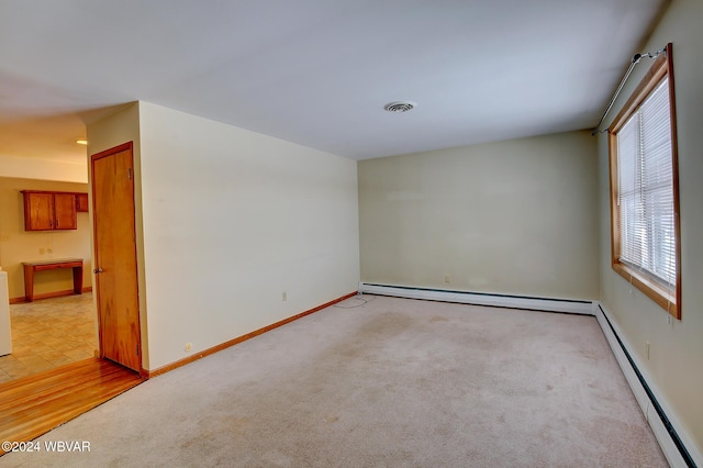 spare room featuring a baseboard radiator, visible vents, and light colored carpet