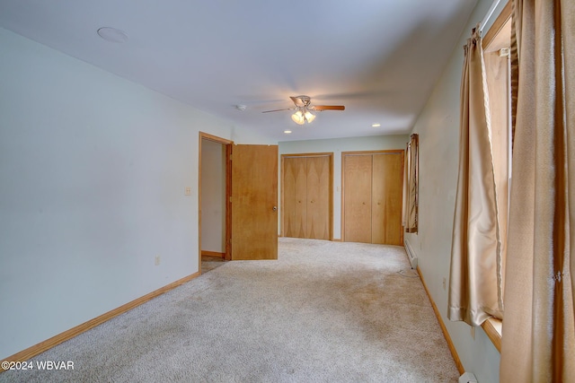 unfurnished room with light carpet, a baseboard heating unit, ceiling fan, and baseboards