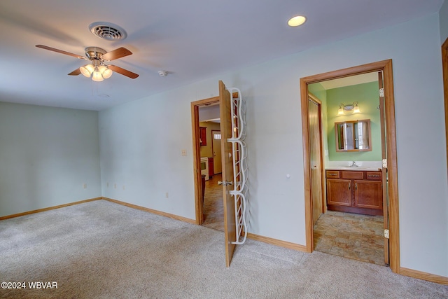 empty room featuring light colored carpet, a sink, a ceiling fan, baseboards, and visible vents