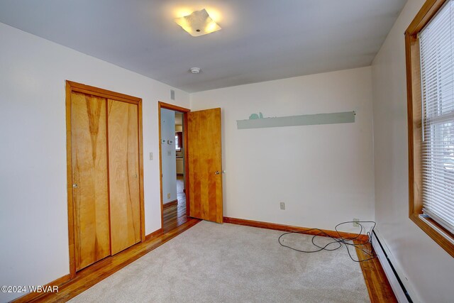 65 Spring St, Lock Haven, PA 17745 - unfurnished bedroom featuring a baseboard heating unit, wood finished floors, a closet, and carpet floors