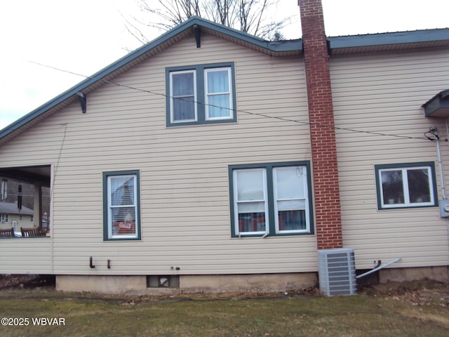 view of home's exterior with a chimney, cooling unit, and a yard