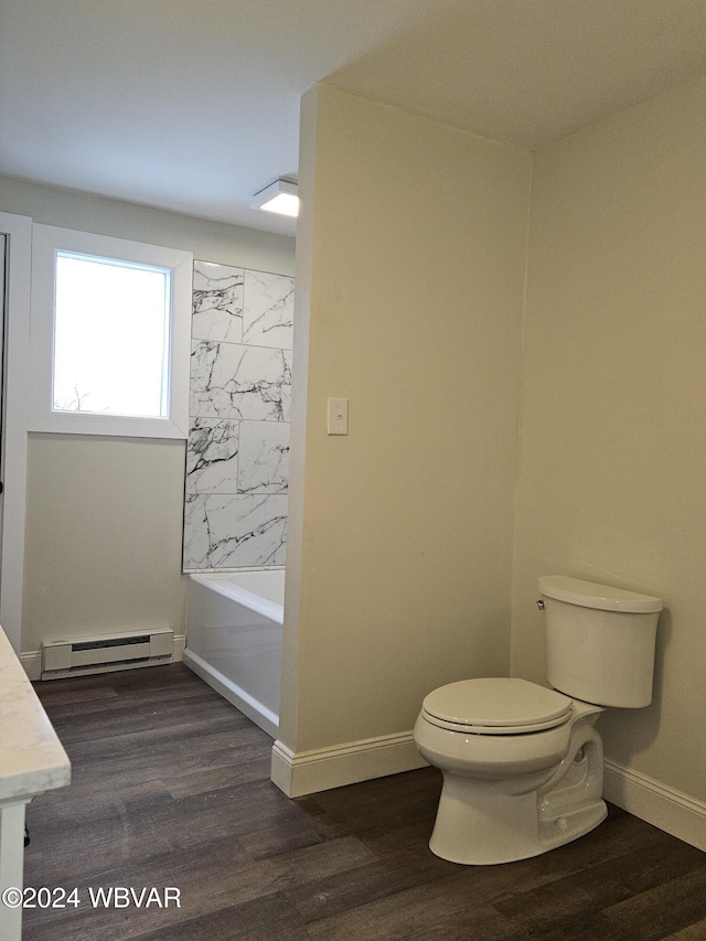 full bathroom featuring tiled shower / bath combo, baseboard heating, hardwood / wood-style floors, toilet, and vanity