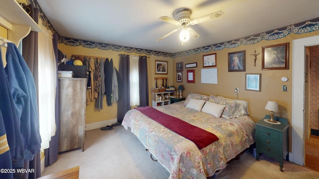 bedroom with light colored carpet, baseboards, and ceiling fan