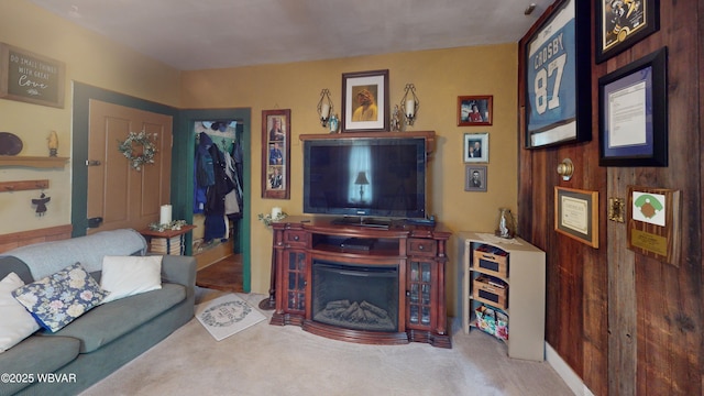 living area featuring wooden walls, a fireplace, and carpet