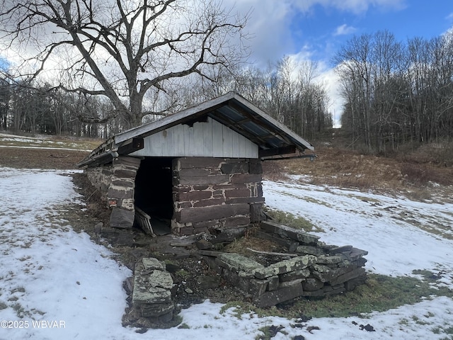 snow covered structure featuring a storage shed and an outdoor structure