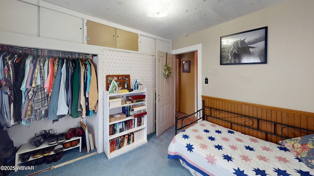 bedroom with carpet floors, wood walls, and wainscoting