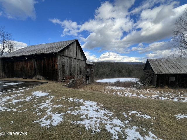 snow covered structure featuring a barn and an outdoor structure