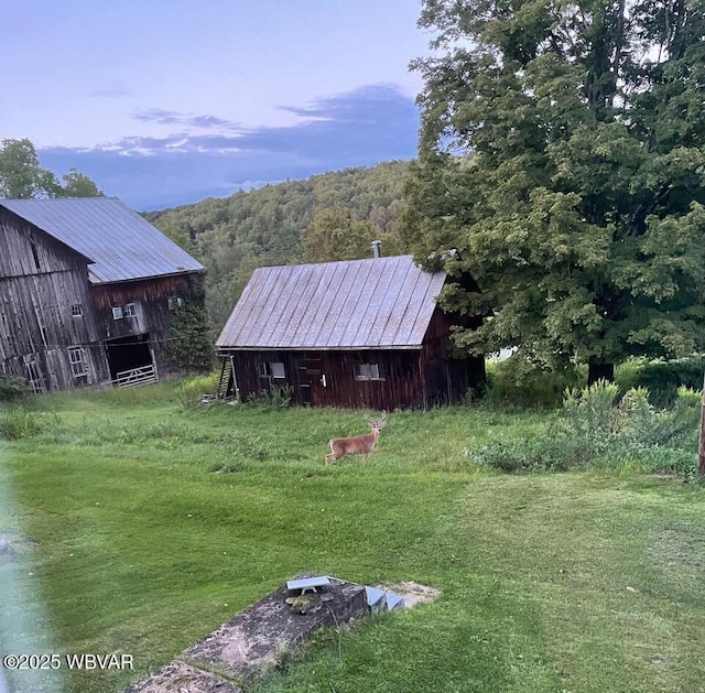 view of yard with a barn, an outdoor structure, and a wooded view