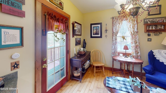 living area with baseboards, a notable chandelier, and light wood-style flooring