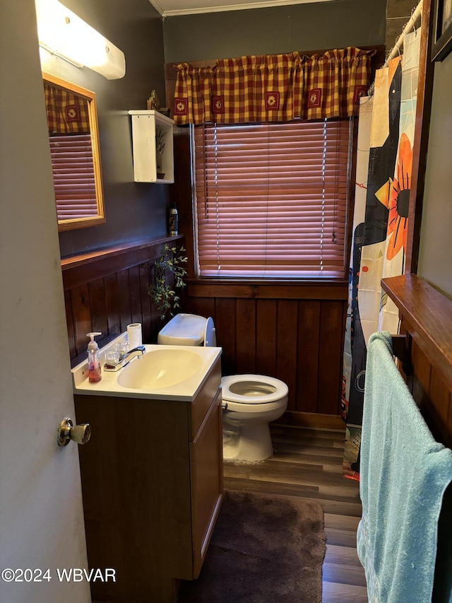 bathroom featuring hardwood / wood-style flooring, vanity, toilet, and wooden walls