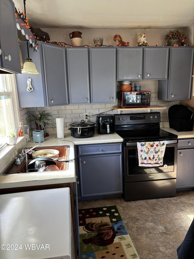 kitchen featuring decorative backsplash, gray cabinetry, sink, pendant lighting, and stainless steel range with electric cooktop