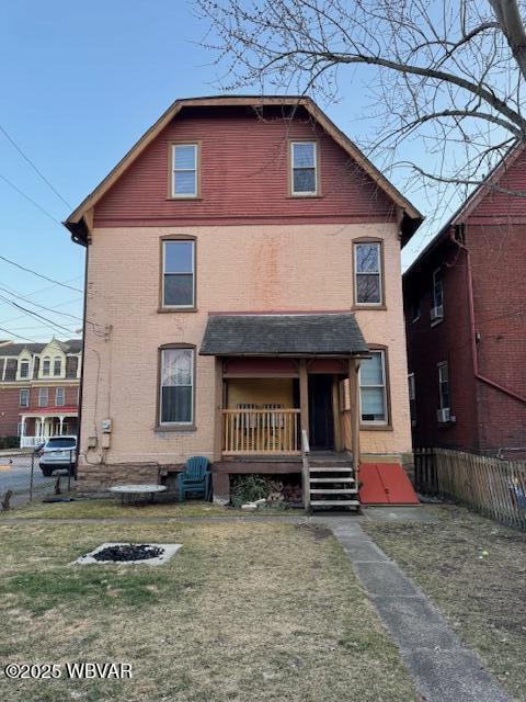 view of front of house with brick siding, a front yard, and fence