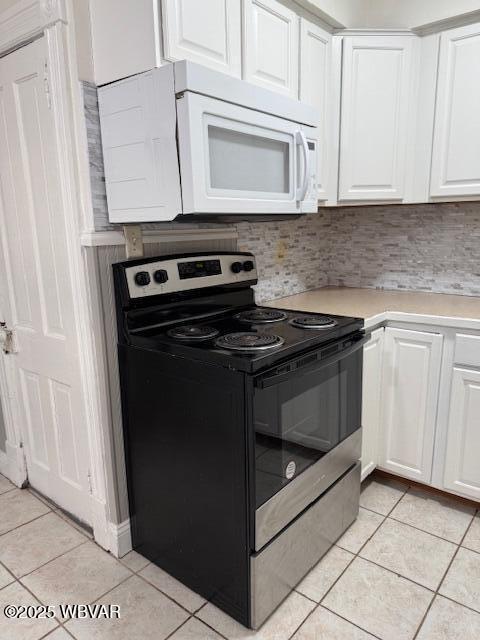 kitchen with black electric range oven, white cabinetry, light tile patterned flooring, light countertops, and white microwave