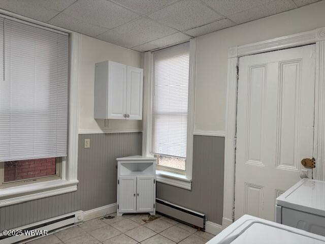 laundry area with light tile patterned floors, a baseboard radiator, a wainscoted wall, and laundry area