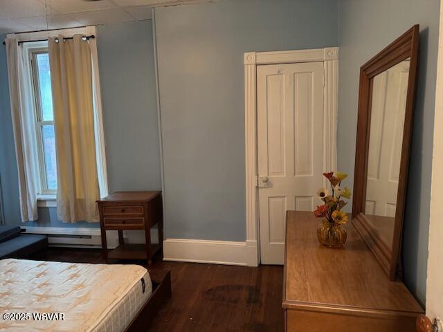 bedroom with a baseboard radiator, baseboards, and wood finished floors