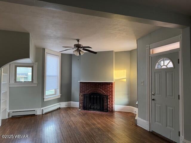 foyer featuring a ceiling fan, baseboards, wood finished floors, a baseboard radiator, and a fireplace