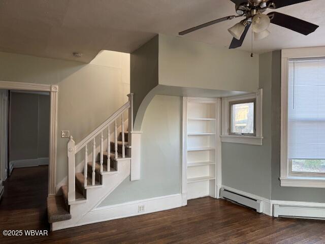 staircase featuring wood finished floors, arched walkways, baseboard heating, and ceiling fan