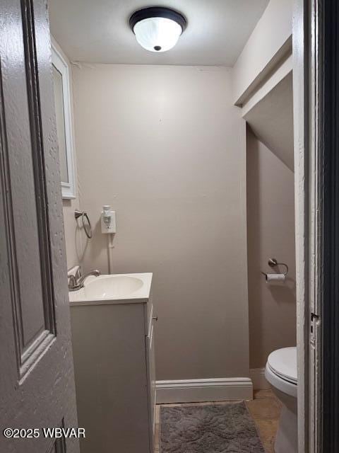 half bath with toilet, vanity, and baseboards