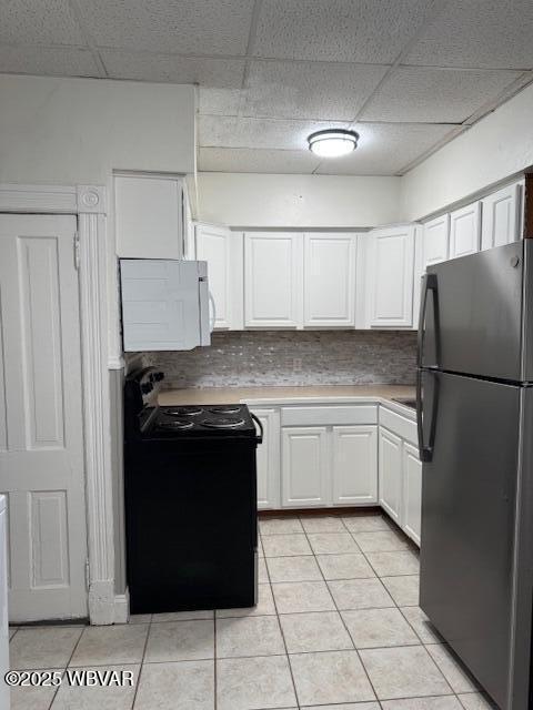 kitchen featuring light tile patterned floors, black appliances, white cabinets, light countertops, and tasteful backsplash