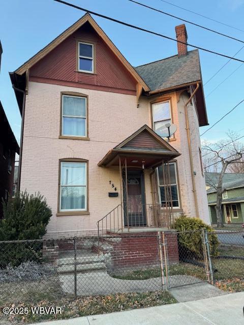 view of front of house featuring a fenced front yard, a chimney, and brick siding