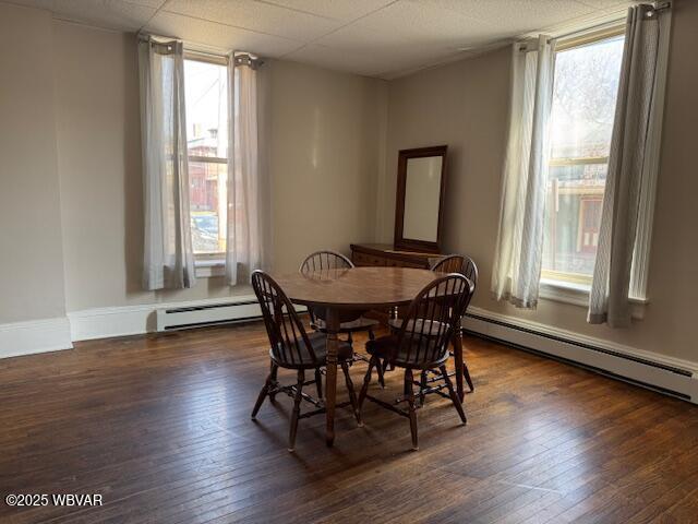 dining space featuring a baseboard heating unit, baseboards, baseboard heating, and hardwood / wood-style flooring