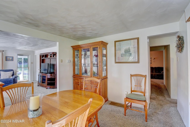 dining room with light colored carpet and a textured ceiling