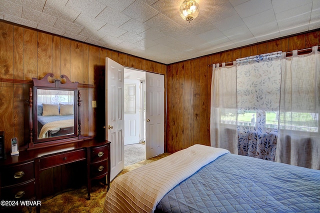 carpeted bedroom featuring wood walls