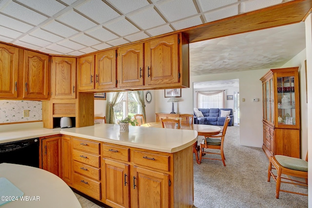 kitchen with kitchen peninsula, a drop ceiling, light colored carpet, and black dishwasher