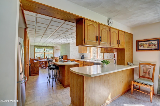 kitchen featuring kitchen peninsula, a kitchen breakfast bar, stainless steel fridge, and a kitchen island