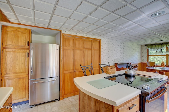 kitchen with range with electric stovetop, stainless steel refrigerator, and a kitchen island