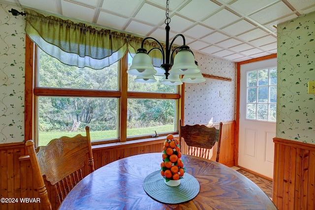 dining space featuring a wealth of natural light, wooden walls, and an inviting chandelier