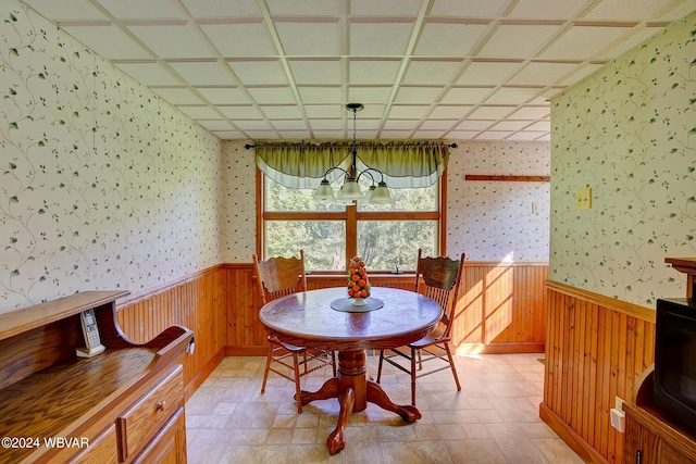 dining area featuring a notable chandelier and wood walls