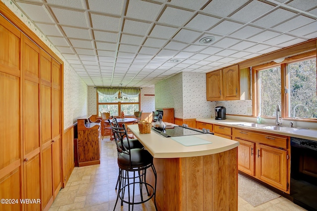 kitchen featuring a breakfast bar, sink, a kitchen island, and black appliances