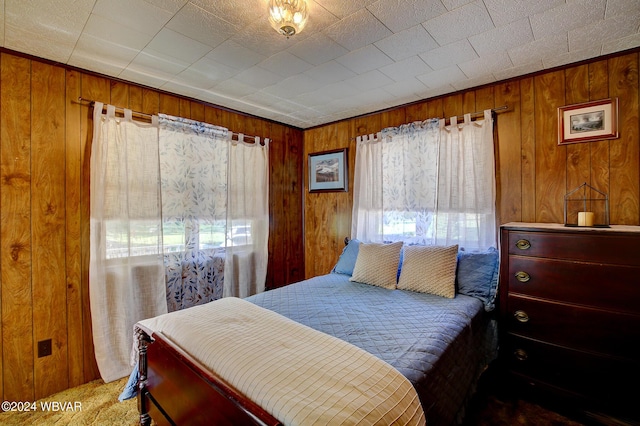 bedroom with carpet flooring and wooden walls