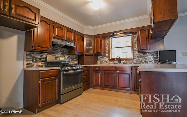 kitchen featuring decorative backsplash, stainless steel gas range oven, crown molding, sink, and light hardwood / wood-style floors