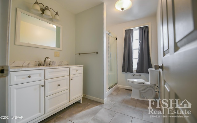 bathroom with tile patterned floors, vanity, a shower with shower door, and toilet